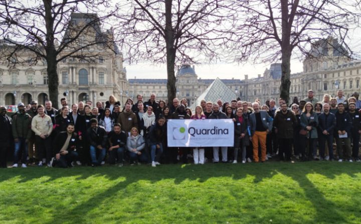 Groupe devant la pyramide du Louvre à Paris avec bannièere du logo Quardina